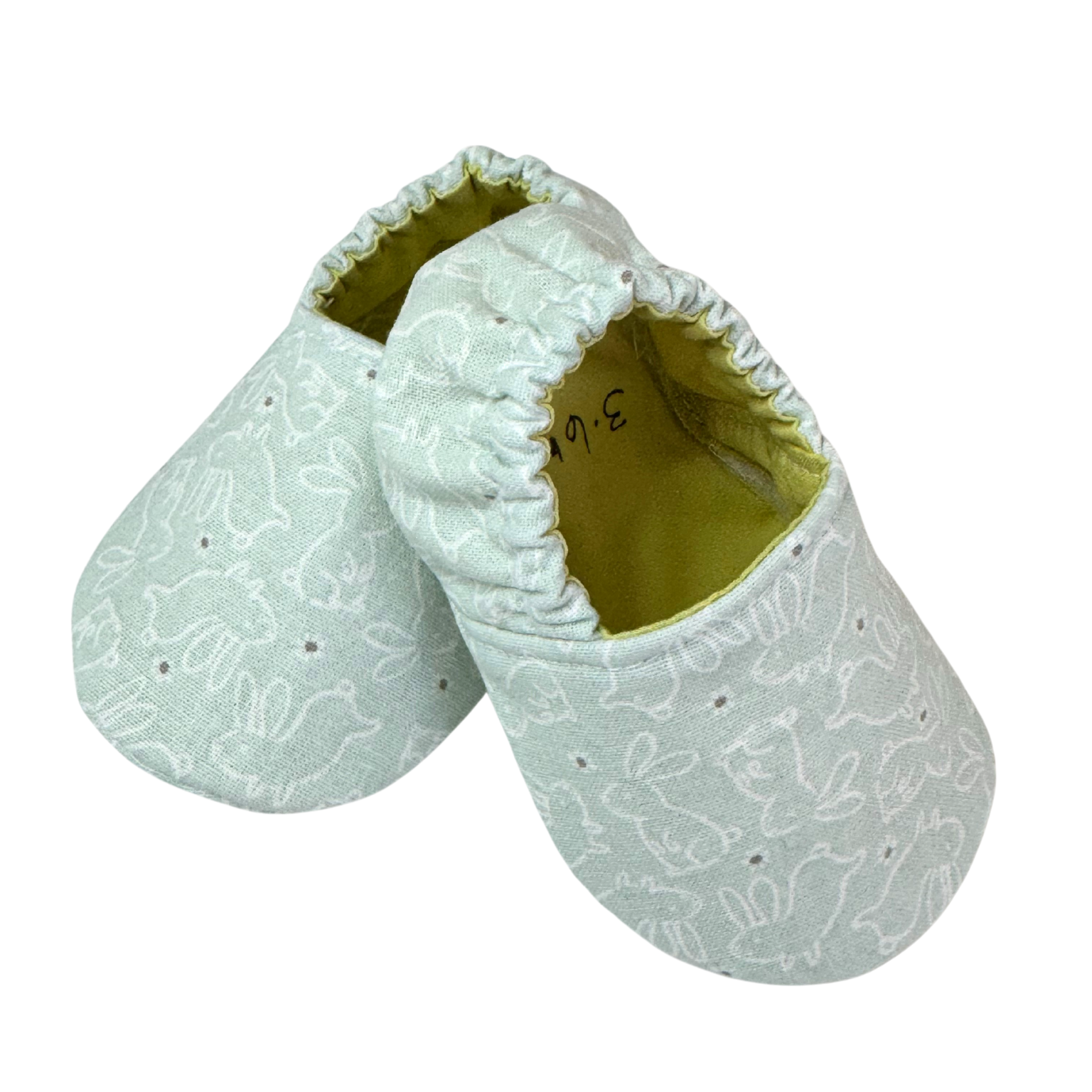 “Side view of handmade soft sole baby shoes with white bunny line art on mint fabric, 3-6 months”

