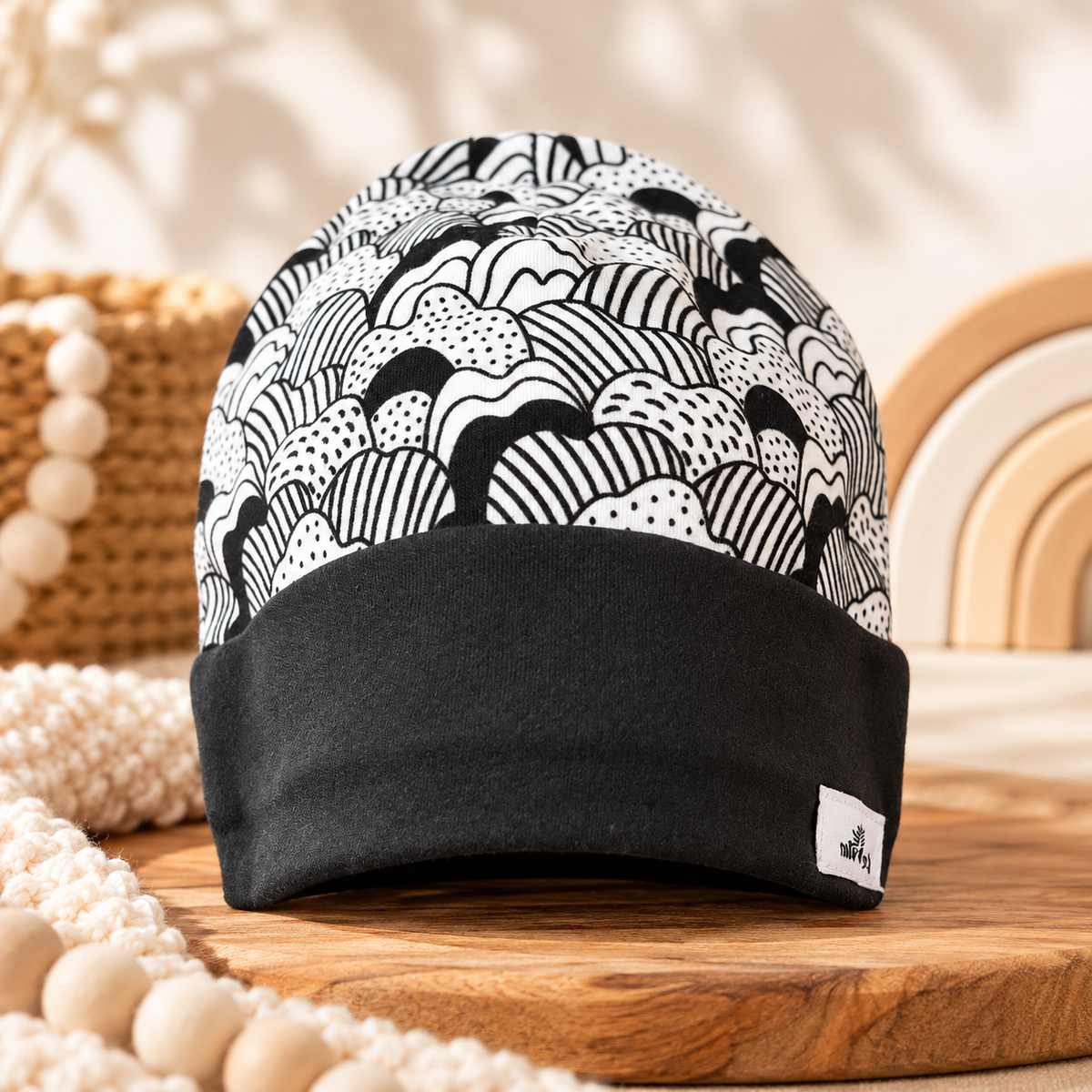 Monochrome waves black and white organic cotton baby beanie with black folded cuff, styled hero photo