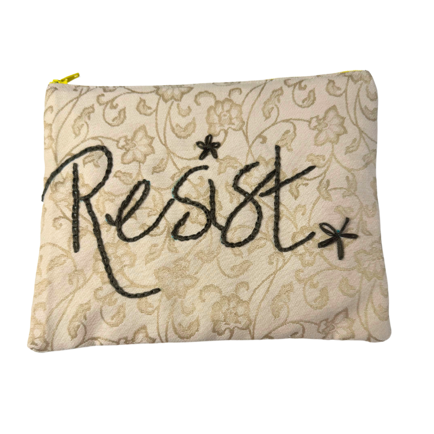 Clutch with “Resist” hand embroidery on beige floral background
