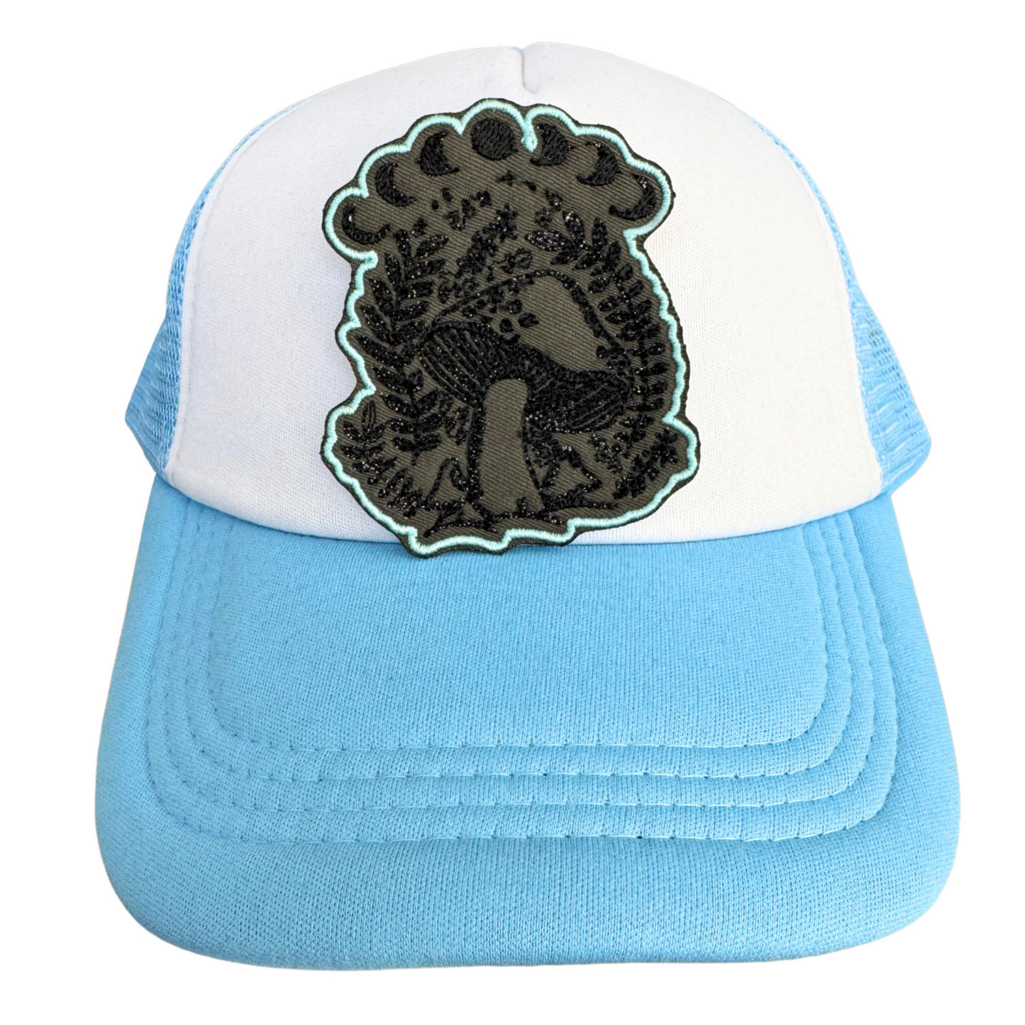 Blue and white trucker hat styled with the Mushroom Moon Phase embroidered patch, perfect for gothic and nature-inspired fashion.

