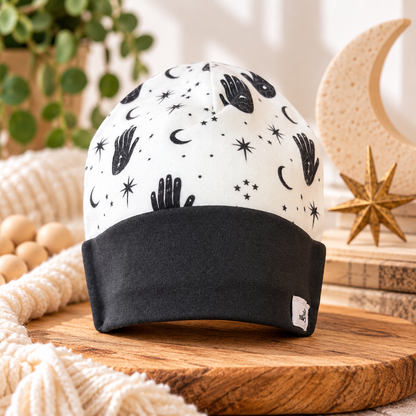 Mystical hands, crescent moons and stars baby beanie in black and white with black cuff, styled product photo