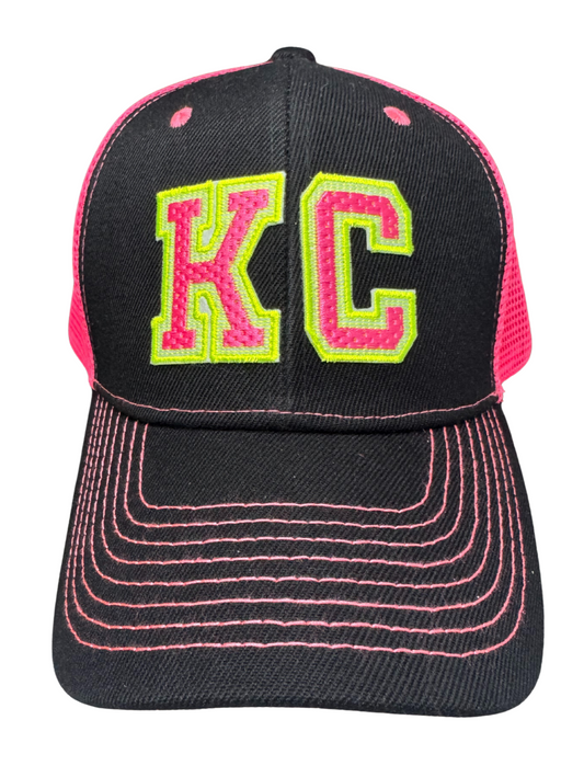 Front view of black trucker hat with neon pink stitching and neon pink and yellow varsity KC patch
