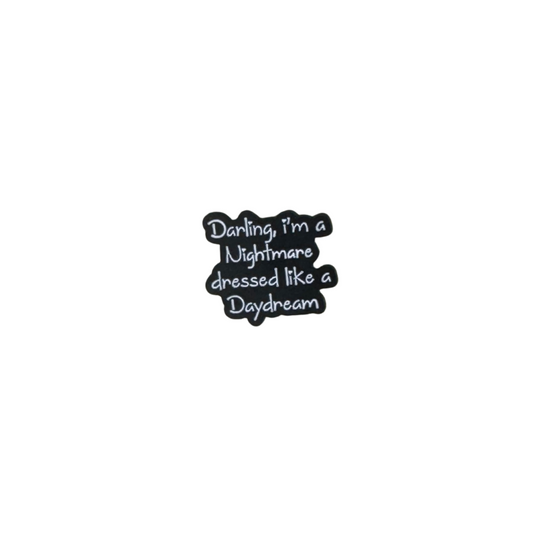 Enamel pin reading “Darling, I’m a nightmare dressed like a daydream” on white background

