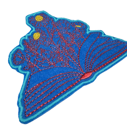 Side close-up of open book floral iron-on patch with yellow and red details

