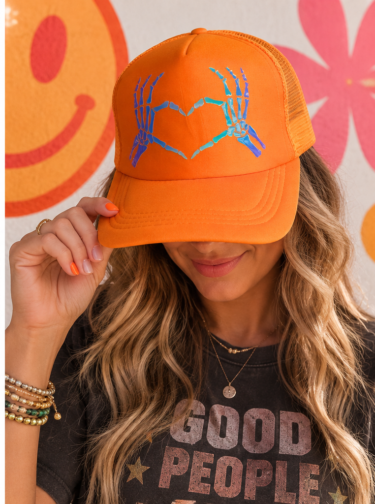 Woman wearing orange skeleton heart hands trucker hat