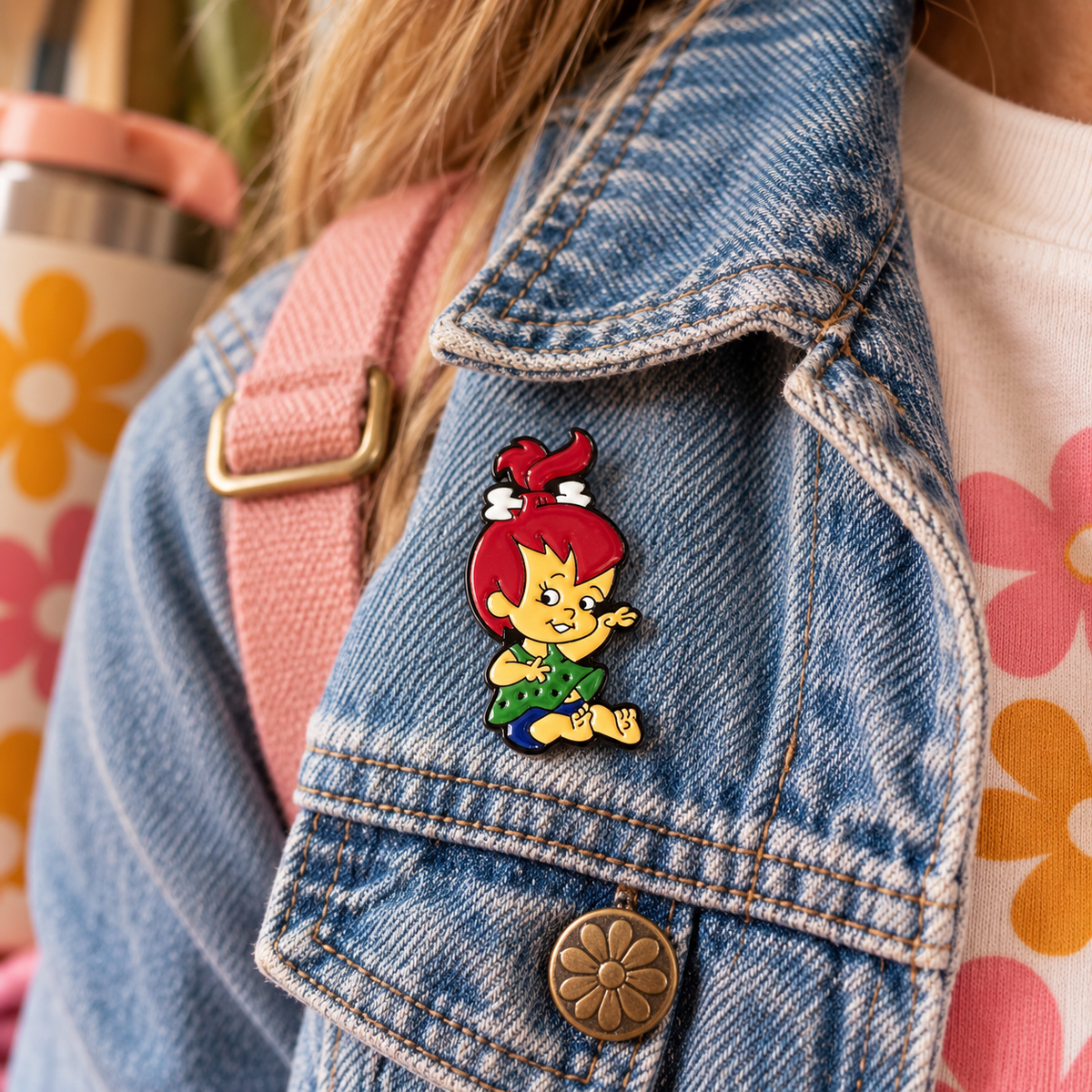 Pebbles Flintstone enamel pin styled on a denim jacket