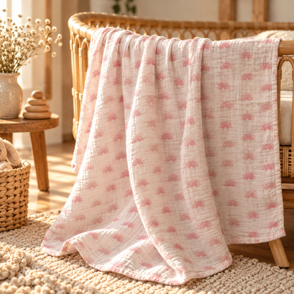 Blush rainbow cotton gauze baby swaddle styled in a warm nursery