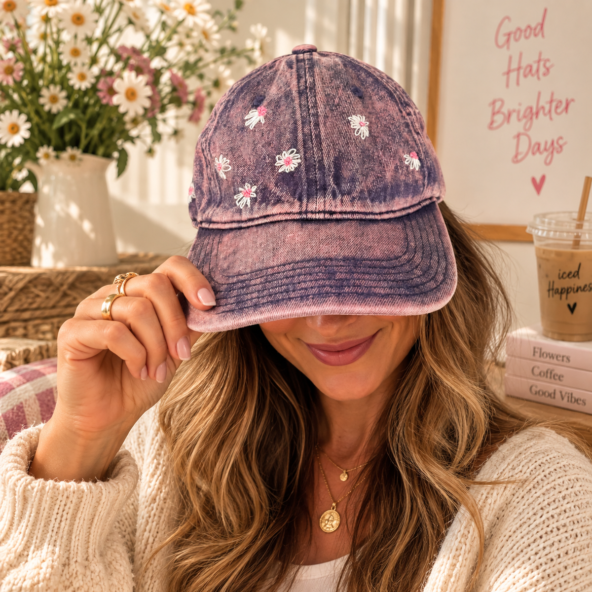 Woman wearing pink stone-wash baseball cap with hand-embroidered daisies