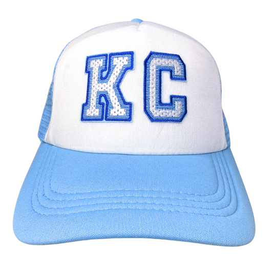 Front view of powder blue and white trucker hat with royal blue and white KC varsity patch
