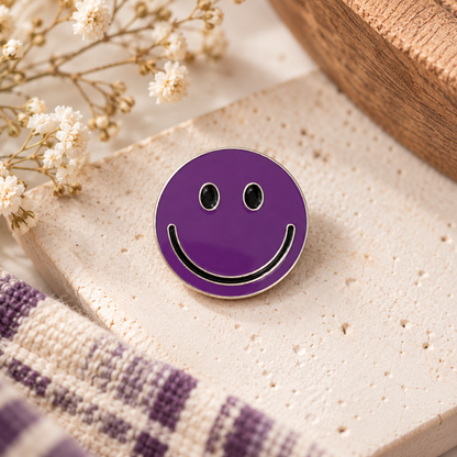 Purple smiley face enamel pin with black smile and silver outline, styled hero