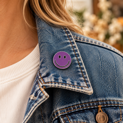 One-inch purple smiley face enamel pin worn on a denim jacket lapel