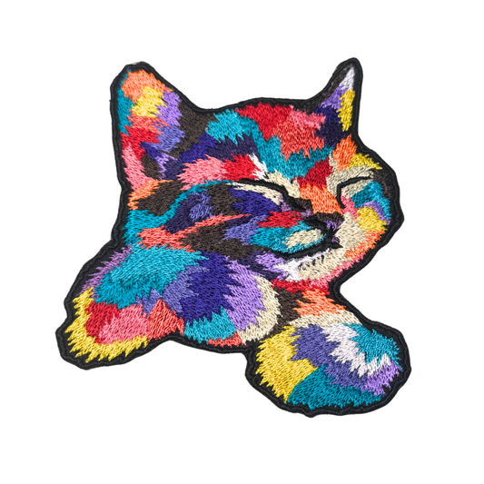 Brightly colored embroidered patch of a sleeping cat in rainbow hues
