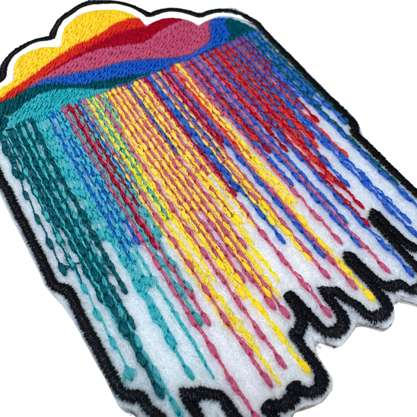 Closeup angled view of rainbow cloud drip embroidered patch

