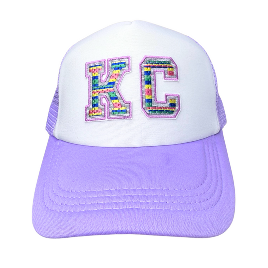 Front view of lilac and white KC trucker hat with multicolor rainbow-striped varsity patch
