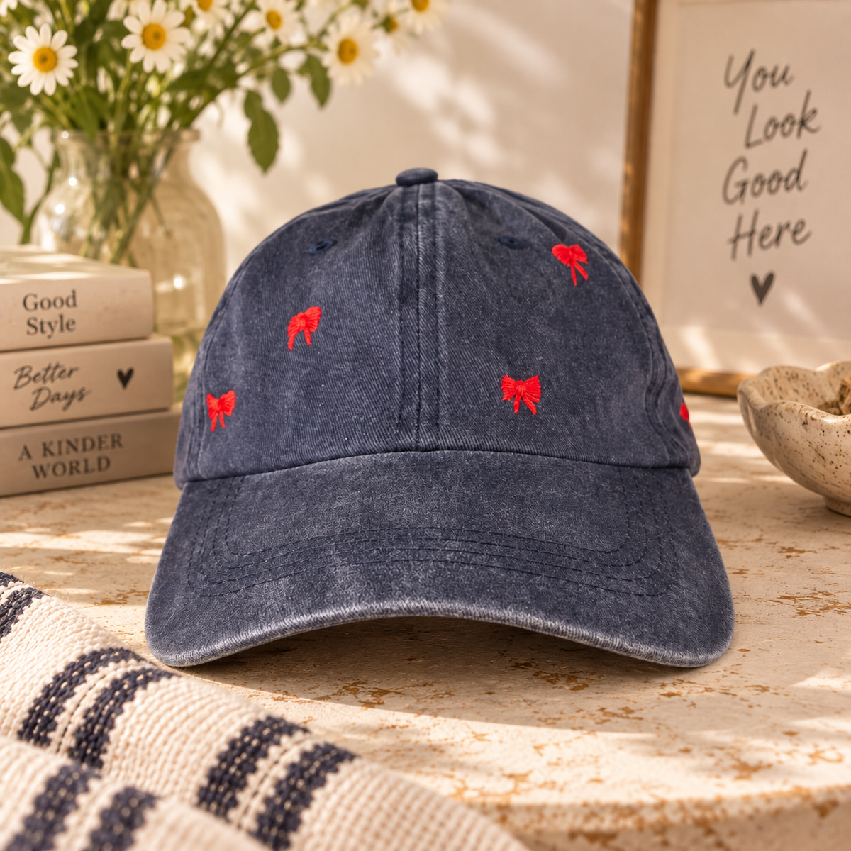 Navy blue baseball hat with hand-embroidered red bows in a warm styled setting