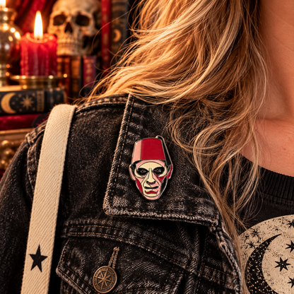 Red fez horror ghoul enamel pin worn on a charcoal denim jacket