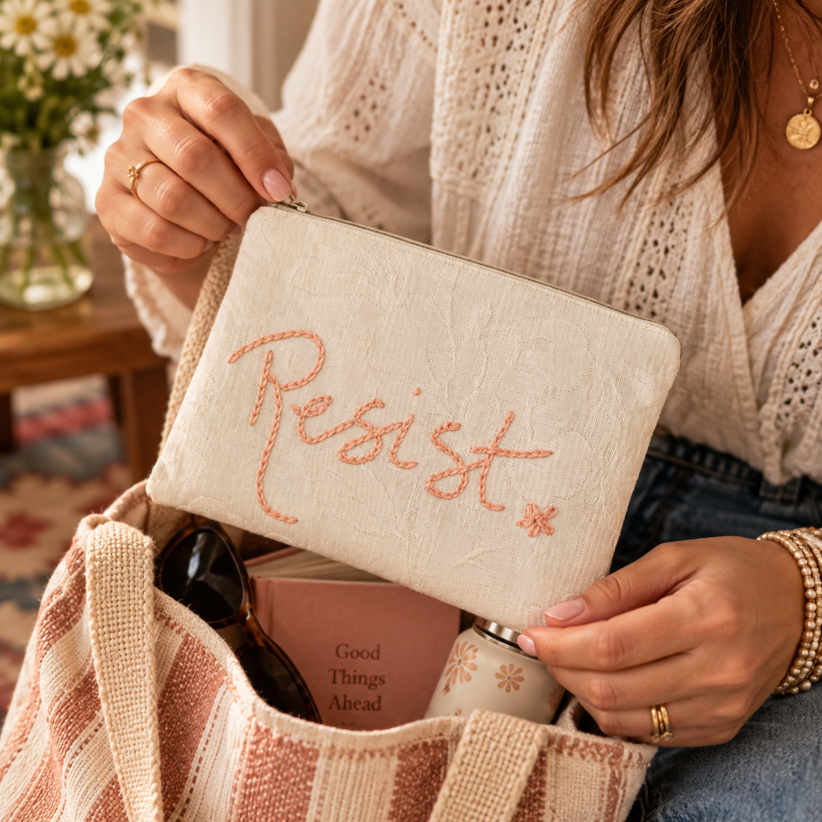 Woman holding hand-embroidered Resist zipper clutch in a warm lifestyle scene