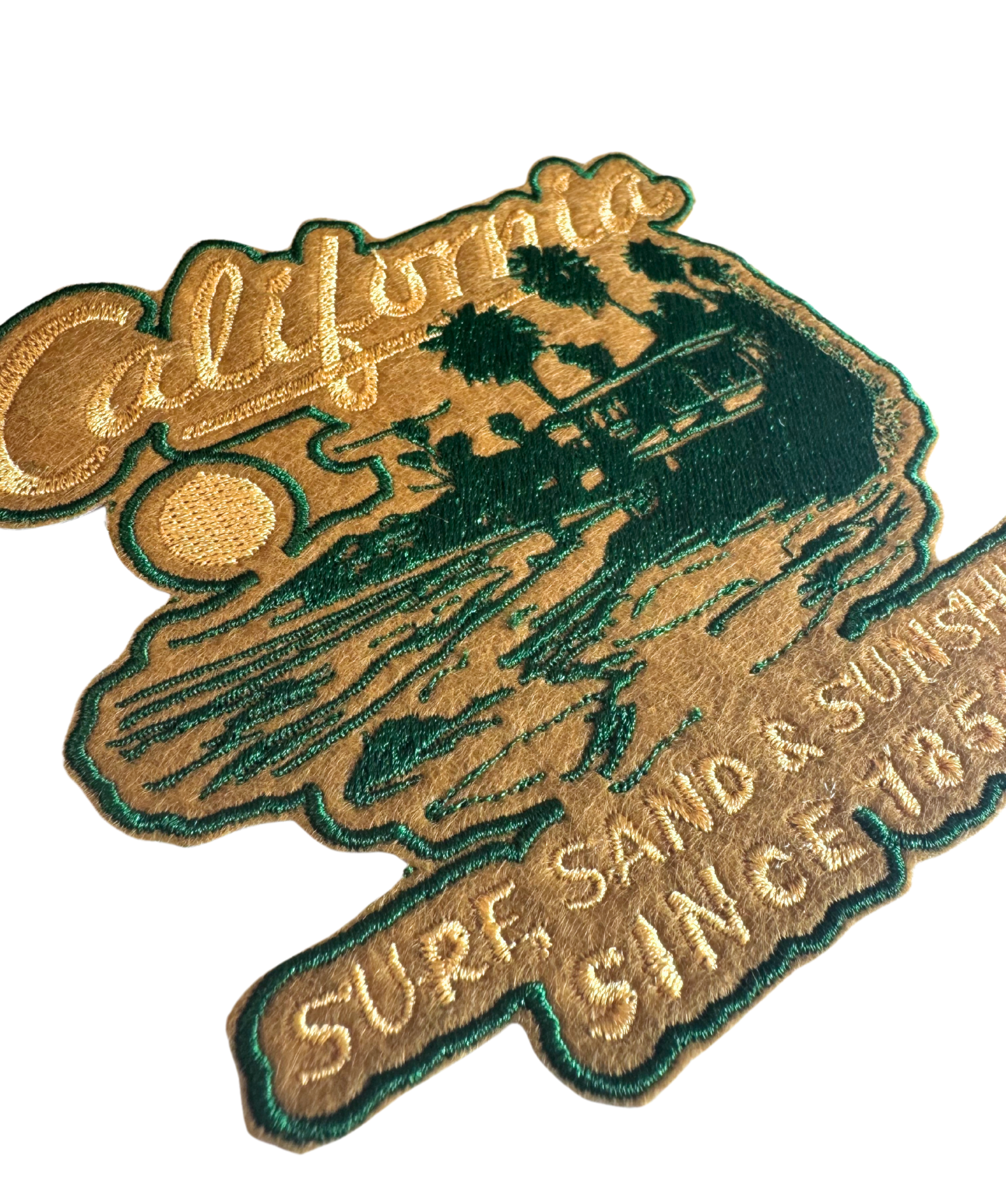 Close-up of vintage-style California patch showing gold and green embroidery with retro sunset

