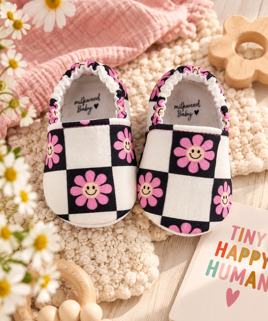 Smiley flower checkerboard baby moccasins styled in a playful boutique flat lay