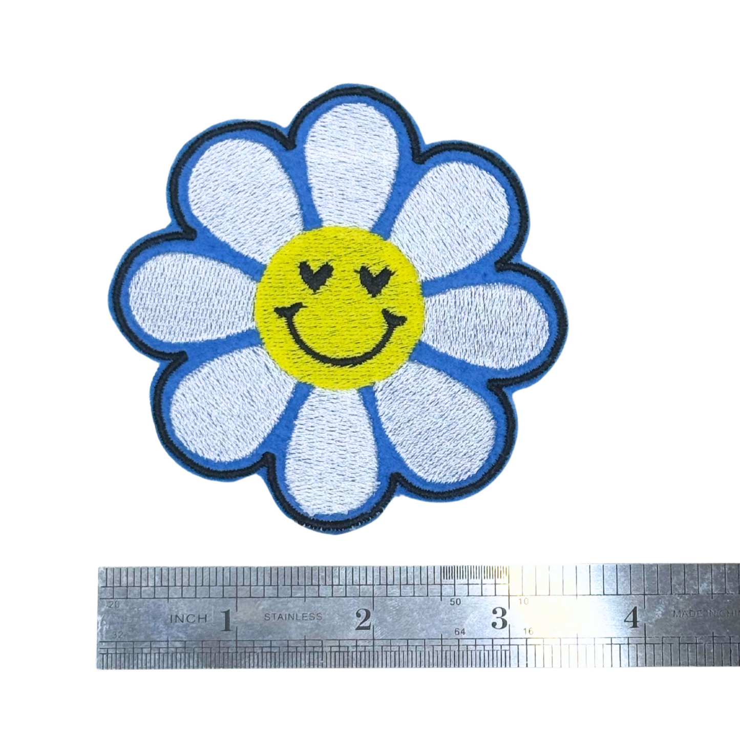 Blue daisy smiley patch next to ruler for size reference