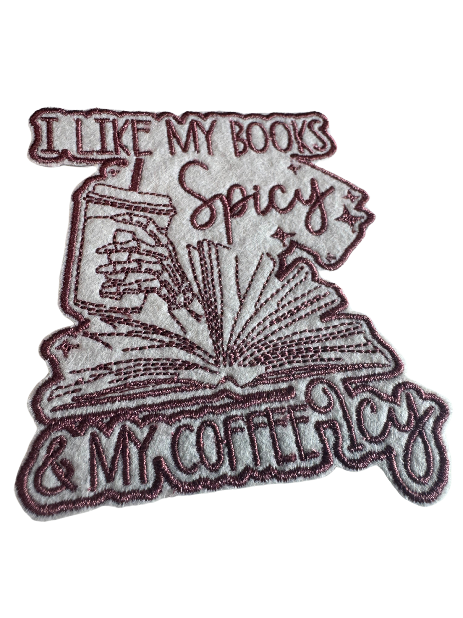Close-up of spicy book lover patch with burgundy embroidery and iced coffee detail

