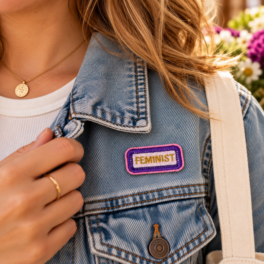 Small FEMINIST embroidered patch in suffragette colors on a denim jacket