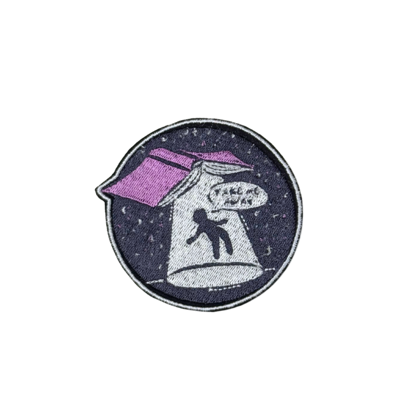 Close-up of an embroidered "Take Me Away" UFO abduction patch featuring a book with a beam of light pulling a figure into space.
