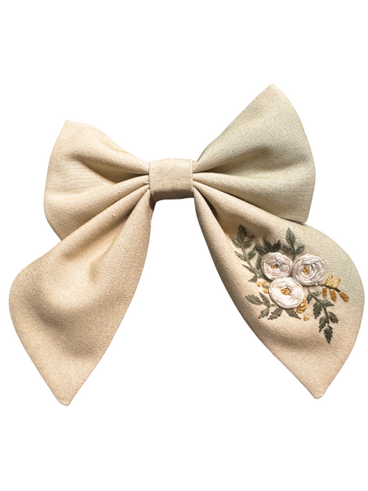 Beige bow with floral embroidery on a white background