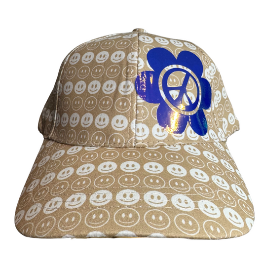 Beige cap with smiley face pattern and blue peace symbol on a white background