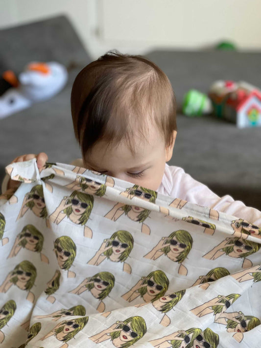 Baby with Swiftie Swaddle Blanket featuring printed Taylor Swift design.