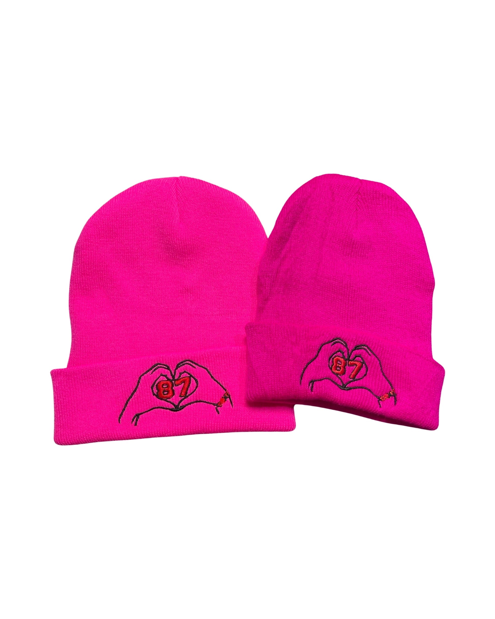 picture of adult and child size neon pink beanies embroidered with two hands forming a heart with the number 87 inside the heart