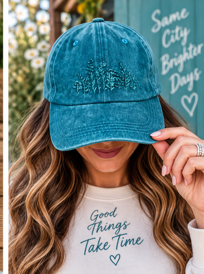 Model wearing teal hand-embroidered wildflower hat