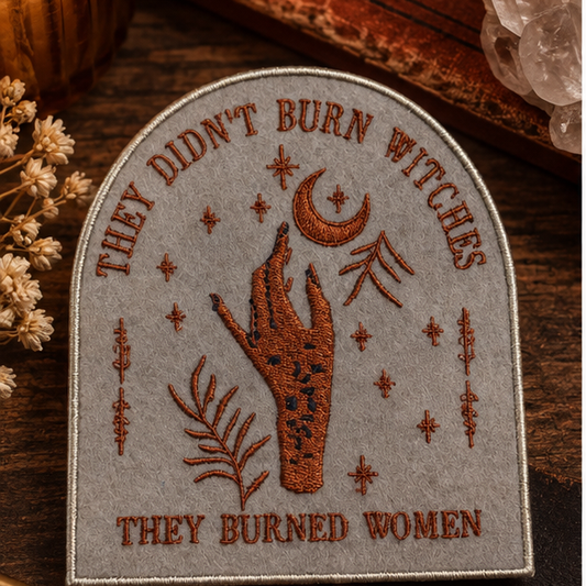They Didn't Burn Witches embroidered patch styled with warm witchy books, crystals and dried flowers