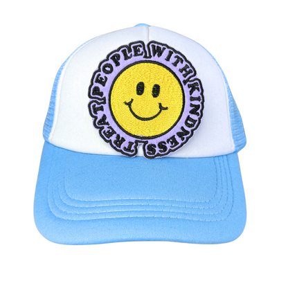 "Blue and white trucker hat featuring an embroidered 'Treat People with Kindness' smiley face patch in yellow and lavender."
