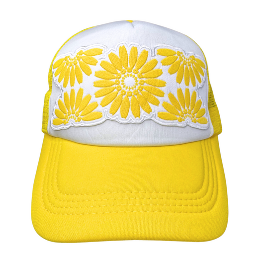 Front view of white and yellow trucker hat with embroidered floral patch inspired by Pyrex Daisy pattern
