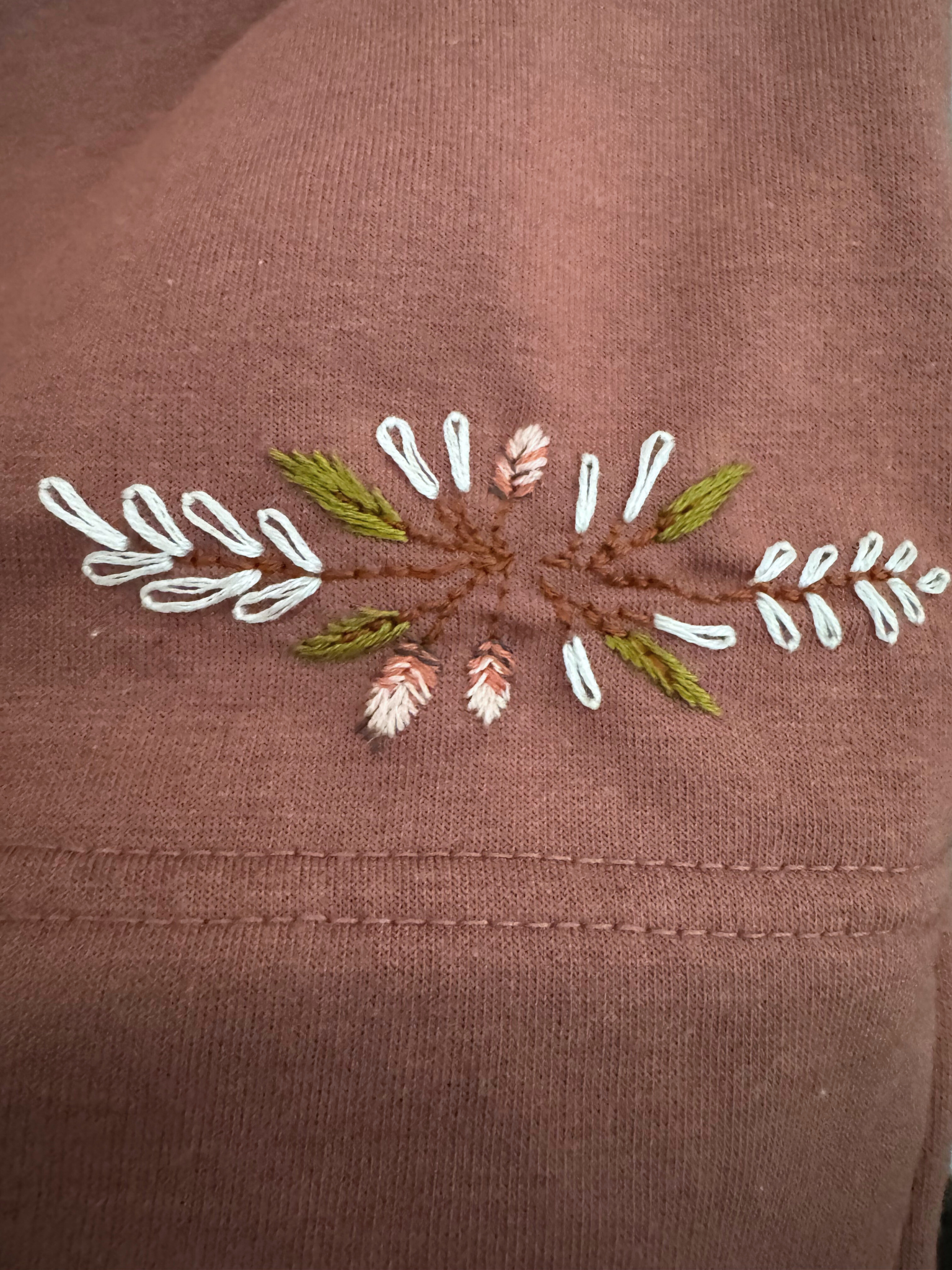 Embroidered floral design on a pink sweatshirt hem