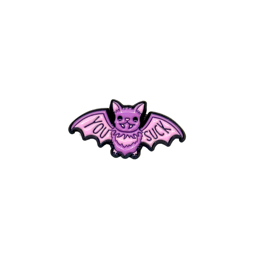 Hero shot of pink and purple vampire bat enamel pin reading “You Suck” on a white background

